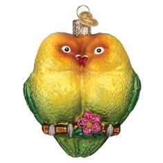 a glass ornament with an orange bird on it's head and flowers in its beak