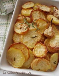 baked potatoes in a white dish with rosemary garnish