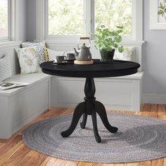 a black table sitting on top of a wooden floor next to a window sill