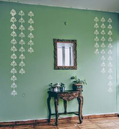 a room with green walls and wooden flooring, decorated with wall stencils