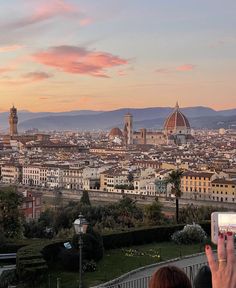 a woman taking a photo with her cell phone in front of the cityscape