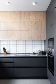 a kitchen with wooden cabinets and black counter tops, along with white tiles on the walls