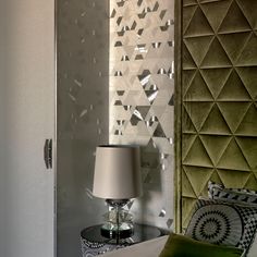 a lamp sitting on top of a table next to a wall covered in geometric designs