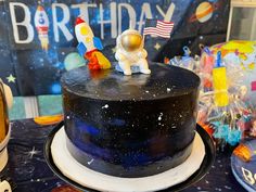 a space themed birthday cake with an astronaut figurine on top, and other decorations around it