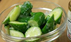 a glass bowl filled with sliced cucumbers next to a jar of mustard