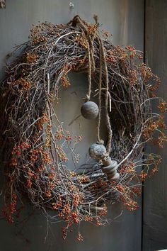 a wreath hanging on the side of a door with balls and branches attached to it