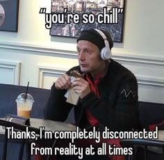 a man sitting at a table with headphones on eating food and drinking from a cup