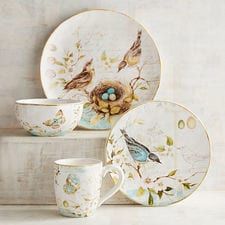 a bird's nest sits on the side of a plate next to two cups and saucers