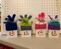 four small boxes decorated like snowmen with christmas decorations on them and tied in twine