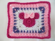 a crocheted square with a pink heart on it and a bow in the center