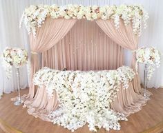 an elaborately decorated stage set up for a wedding ceremony with flowers and drapes