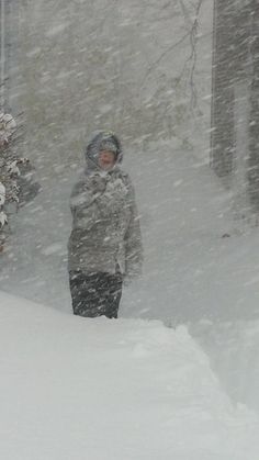 a person standing in the snow with a snowboard on their head and one hand up to his face