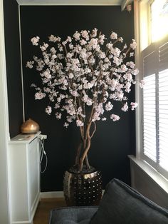 a vase filled with flowers sitting on top of a wooden floor next to a window