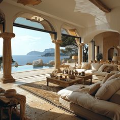 a living room filled with lots of furniture next to a large window overlooking the ocean