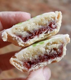 a hand holding two small pastries in it's palm, with jelly filling them