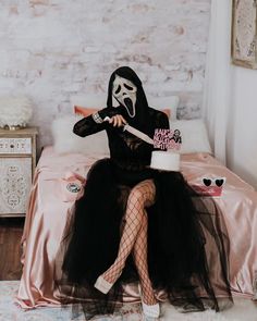 a woman sitting on top of a bed wearing a mask and holding a knife in her hand