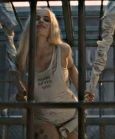 a woman in white shirt standing behind bars