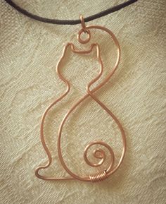 a wire wrapped necklace with a cat on it's back and the letter s in the middle