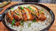 a bowl filled with rice and meat on top of a wooden table