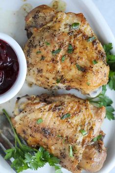 two pieces of chicken on a plate with cranberry sauce