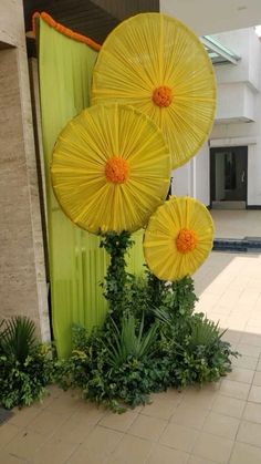 three yellow umbrellas sitting on top of a green pole in front of a building