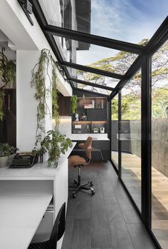 an office with glass walls and plants on the desk