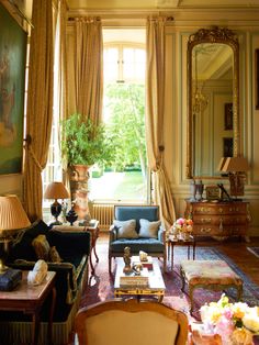 a living room filled with furniture next to a window covered in curtains and drapes