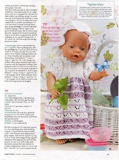 the doll is wearing a white dress and holding a green leaf in her hand while standing next to a wicker basket