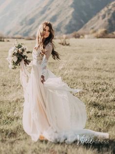 a woman in a wedding dress is walking through the grass with her bouquet on her hand