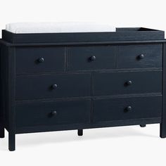 a black dresser with drawers and a baby crib in the bottom drawer, against a white background