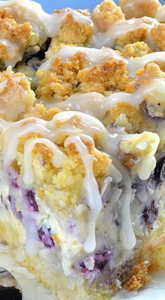 a piece of blueberry crumb cake on a white plate with icing drizzled