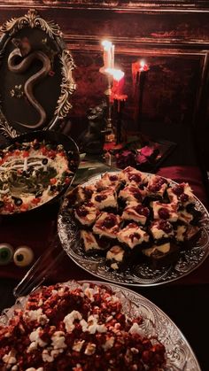 two plates with desserts on them and candles in the background at a halloween party