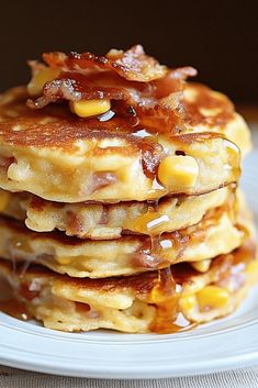 a stack of pancakes covered in bacon and syrup