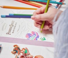 the child is drawing with colored pencils and crayons on the paper next to them