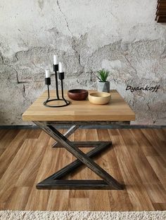 a wooden table with two bowls on it and a metal x frame coffee table in front of a stone wall