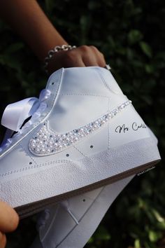 someone is holding a white nike air force high top sneaker with pearls on the side