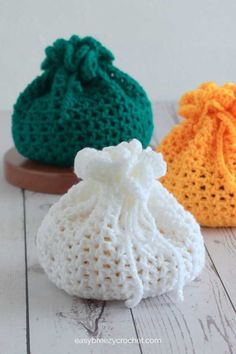 three crocheted bags sitting on top of a wooden table