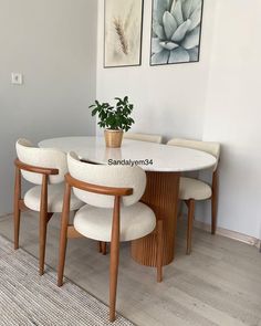 a white table with four chairs and a potted plant on it in the corner