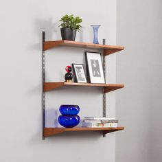 three wooden shelves with pictures and vases on them against a white wall in a room