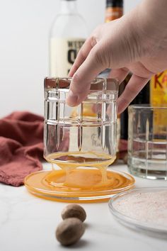 a person is mixing ingredients in a blender on a table with bottles and glasses