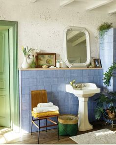 a bathroom with blue tile and green door, sink, mirror and plant in the corner