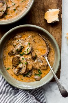 two bowls of soup with mushrooms and parsley on the side, one bowl is full of soup