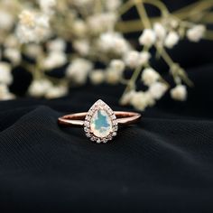 an engagement ring with a pear shaped blue topazte surrounded by small white flowers