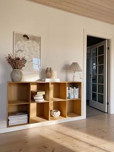 a wooden shelf with books and vases on it in the corner of a room