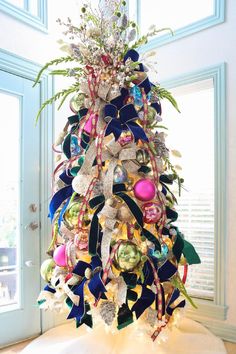 a christmas tree made out of ribbons and other items is shown in front of a window