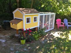 a small yellow chicken house sitting in the middle of a yard