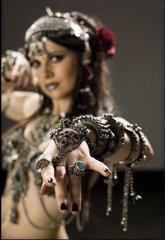 a woman with her hand in the air and wearing jewelry around her neck, pointing at something