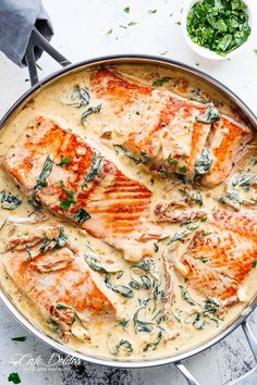 chicken with cream sauce in a skillet on a white surface next to some parsley