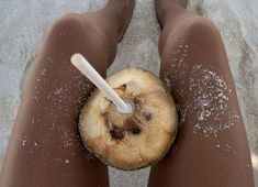 a person standing in the snow holding an apple slice with a straw sticking out of it