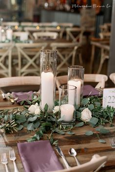 the table is set with candles and greenery for an elegant wedding reception or special event